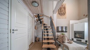 Un interior moderno con una escalera en espiral, una chimenea y una zona de estar acogedora.