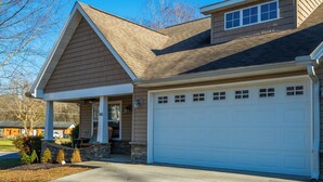 A residential house with a garage, a covered porch, and a stone foundation.