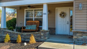 A house with a porch, a bench, and a door with a wreath.