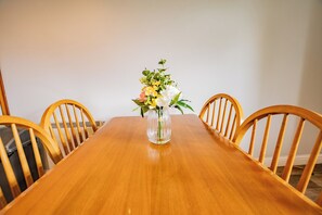 A wooden dining table with a vase of flowers in the center, surrounded by wooden chairs. - Clean & Comfortable 2-Bed Apartment Galway (Galway)