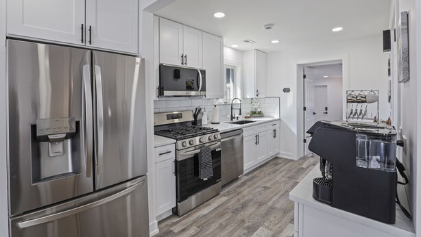 A modern kitchen with stainless steel appliances, white cabinetry, and a built-in oven. - Modern Home Near Rosemont/allstate Arena O'hare 3 Bedroom Home (Des Plaines)