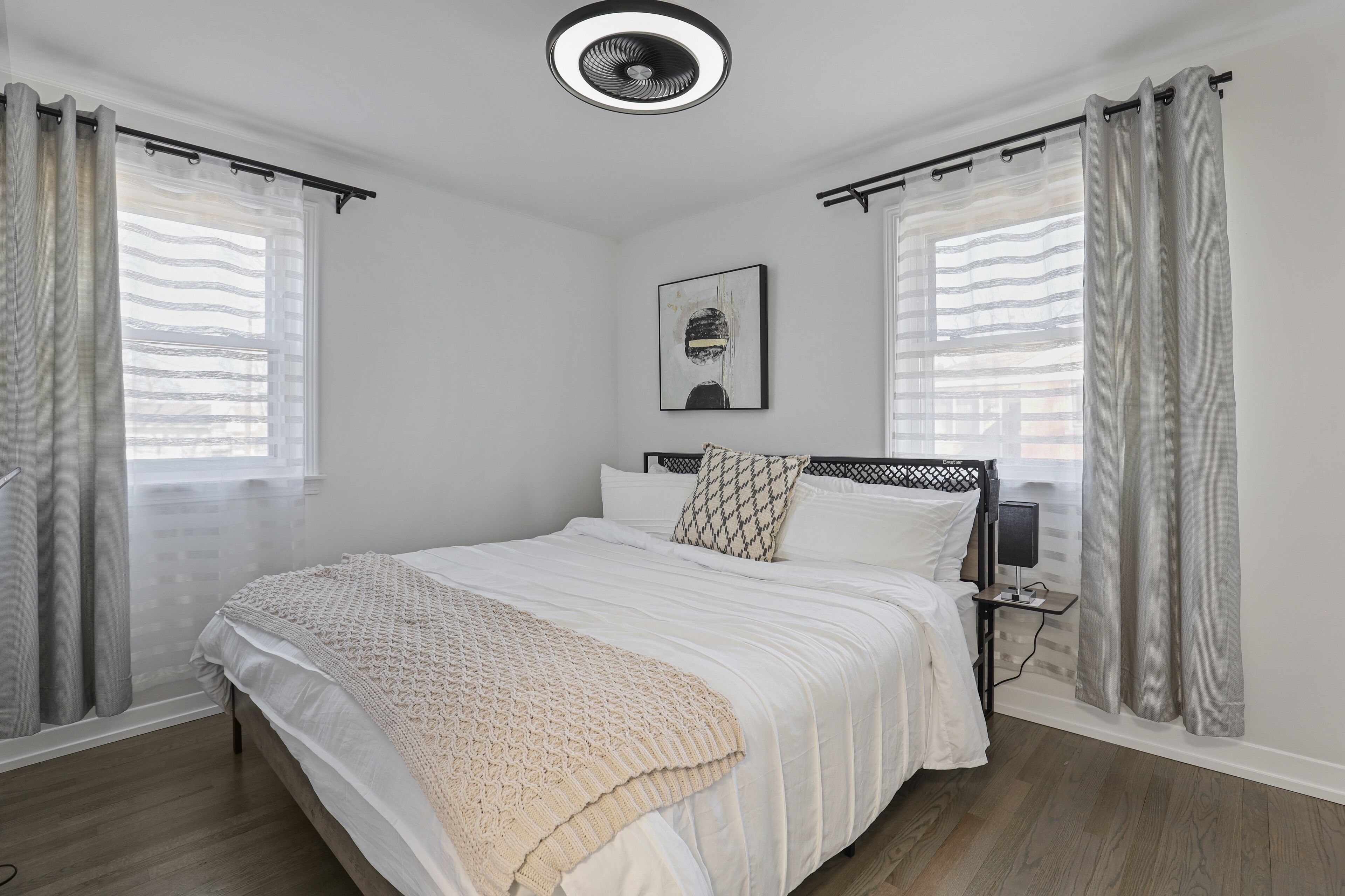 Un dormitorio con una cama, una mesita de noche con lámpara y un ventilador de techo.