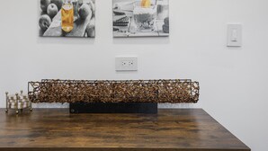 A modern interior with a wooden table, two black and white photographs on the wall, and a decorative metal sculpture. - Modern Home Near Rosemont/allstate Arena O'hare 3 Bedroom Home (Des Plaines)