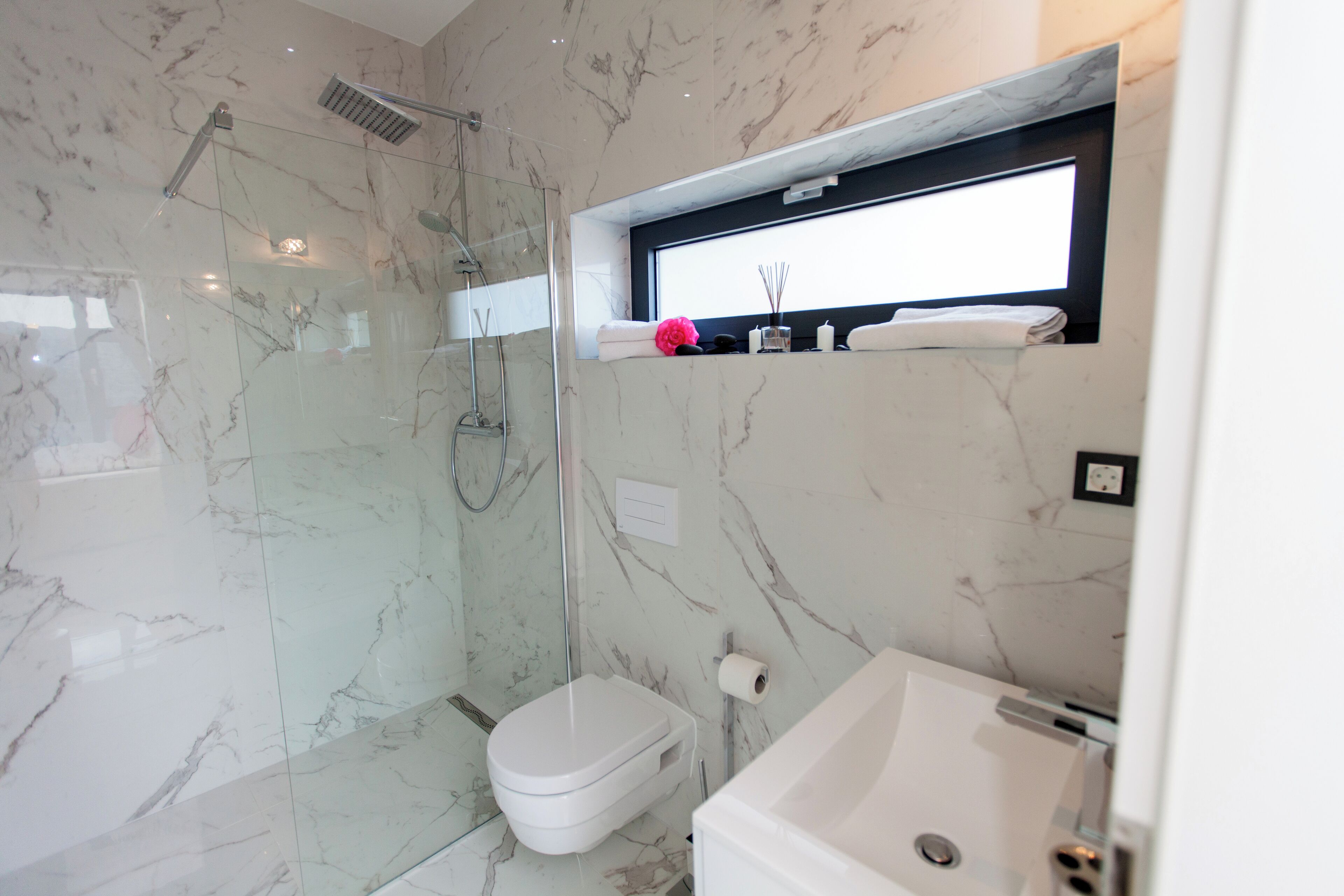 Un bagno moderno con doccia a vetro, water perfetto bianco e vasca idromassaggio integrata.