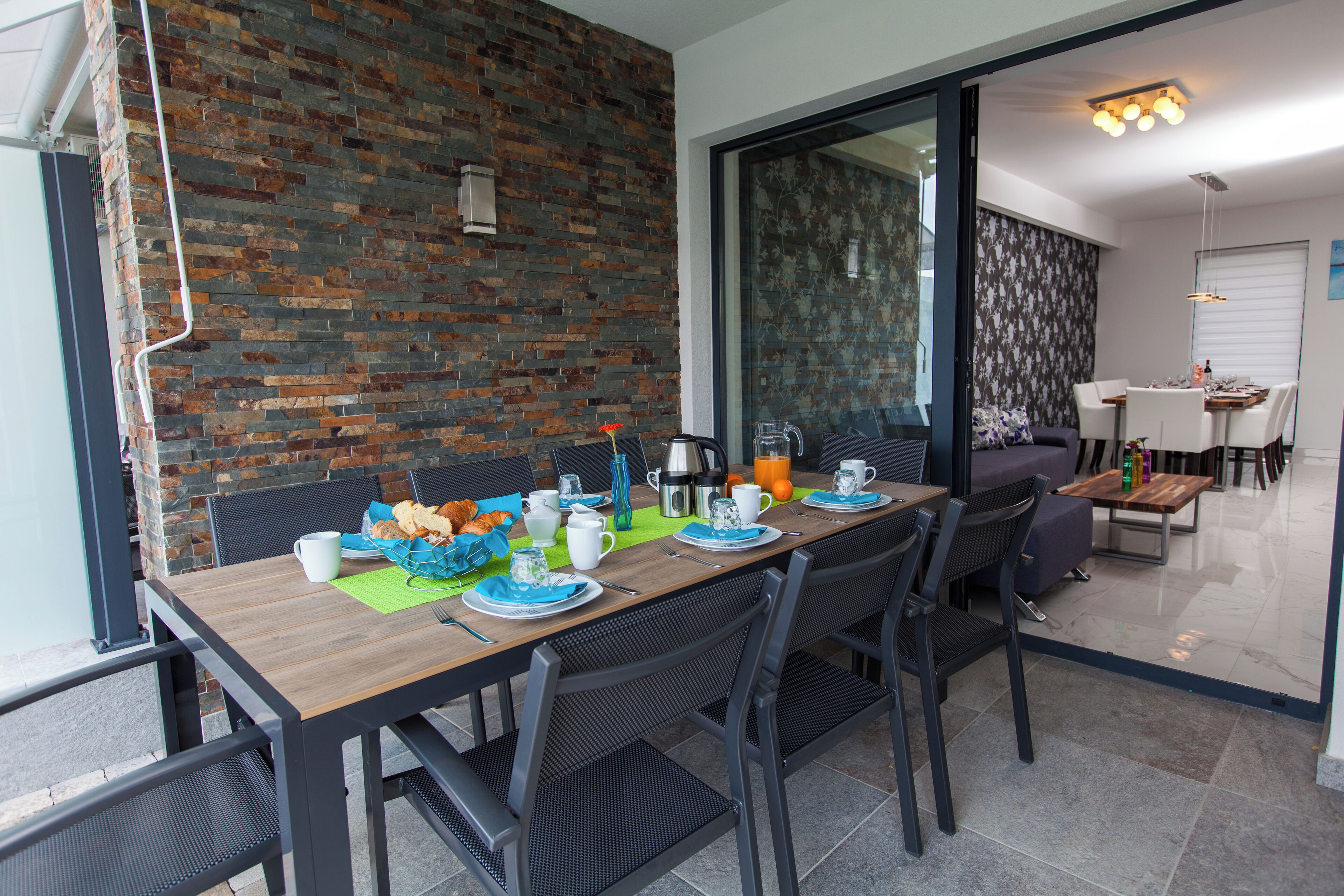 Un comedor con pared de ladrillo, una mesa de madera y sillas negras.