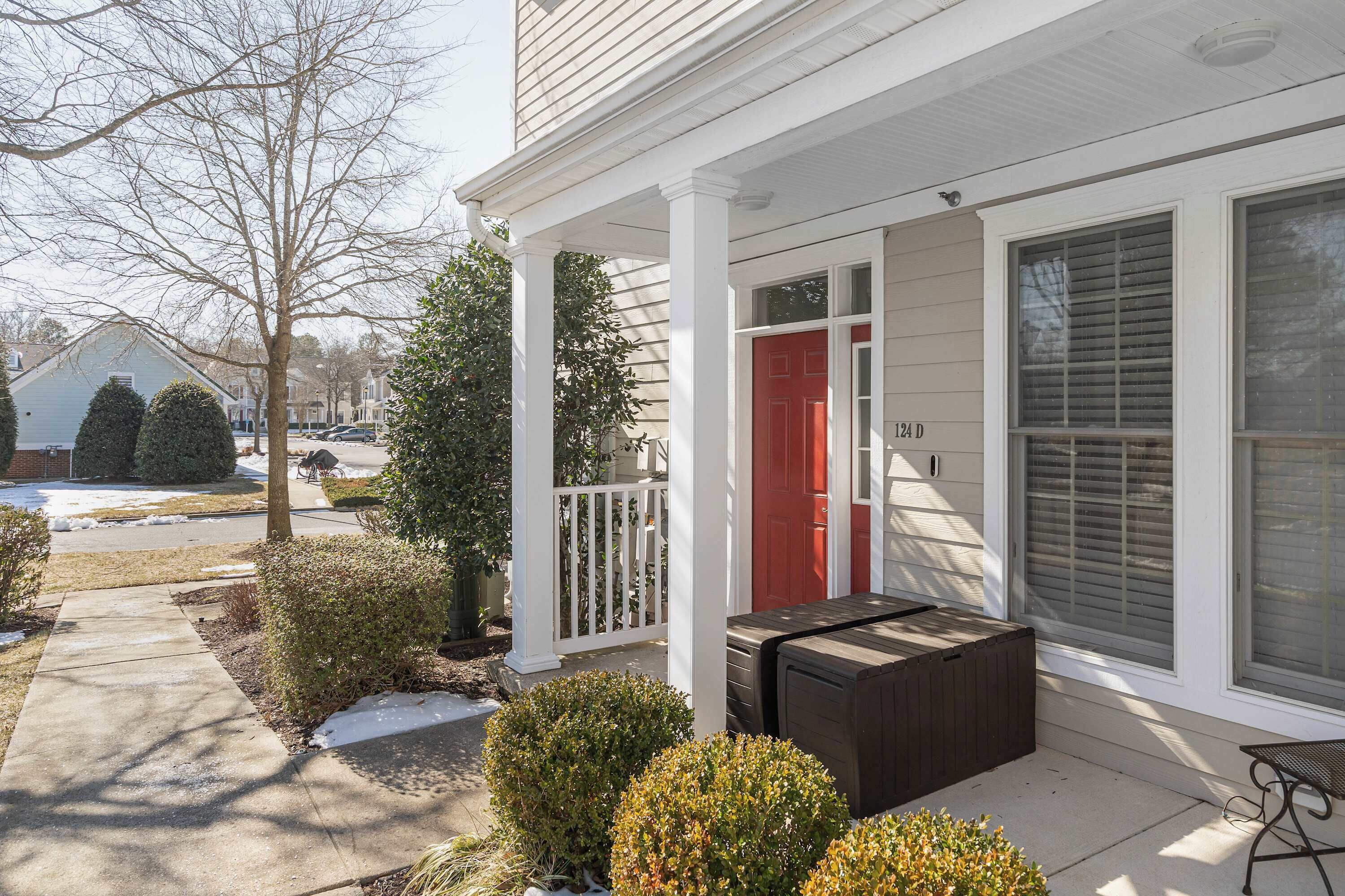 A house with a red door, a covered porch, and a small patio area with a bench.