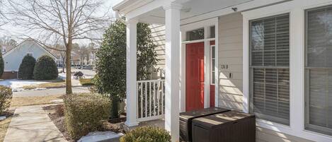 A house with a red door, a covered porch, and a small patio area with a bench.