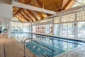 An indoor swimming pool with wooden beams, large windows, and a view of the outside. - Bear Trap Glory Pools & Golf (Ocean View)