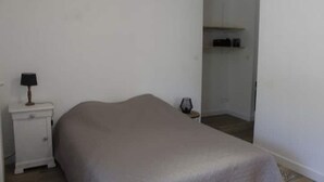 Een slaapkamer met een bed, nachtkastje, lamp en kledingkast.