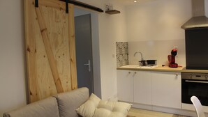 Een moderne keuken met witte kasten, een zwarte oven en een rode koffiezetapparaat.