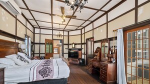Ein traditionelles japanisches Schlafzimmer mit Tatami-Boden, einem großen Bett mit dekorativem Kopfteil, einem Holzschrank und einer Glasschiebetür zu einem Außenbereich.