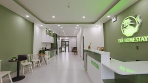 Een receptiegedeelte met een groene wand, een receptiebalie en een zithoek met stoelen en een tafel.