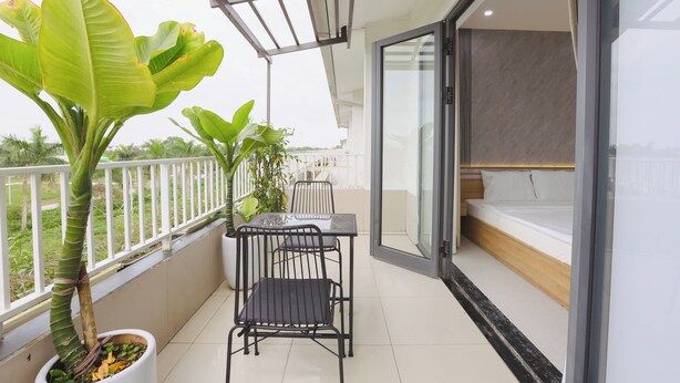 Een balkon met een tafel, stoelen, een plant in pot en een bed met uitzicht.