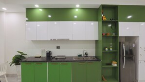 Een keuken met groene kastjes, een roestvrijstalen koelkast en een zwart aanrecht.
