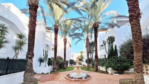 A courtyard with palm trees, a central fountain, and white buildings. - Puerto Rey - Near the beach with private garden (Vera playa)