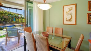 A dining area with wicker chairs and a glass table, overlooking a pool and outdoor seating. - Ground-Floor Maui Eldorado 1 Bedroom Condo Steps to Pool & BBQ | Unit C103 (Kaanapali)