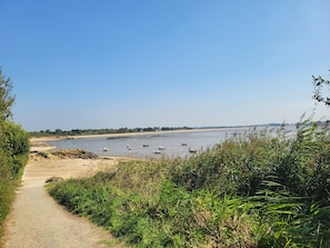 Ein Fluss mit Booten, ein Sandstrand und ein Weg zum Wasser.