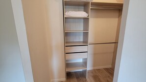 Een inloopkast met houten vloer en witte muren.