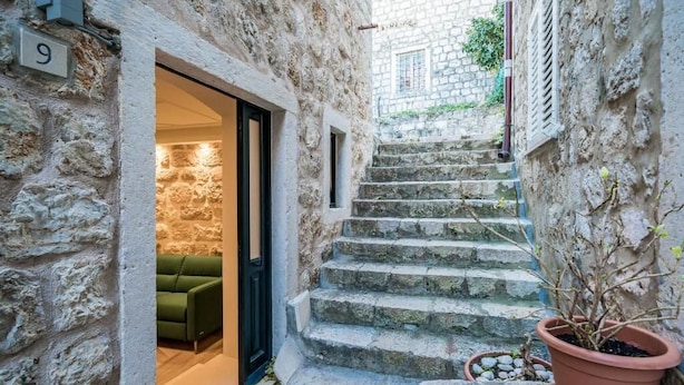 A stone staircase leading to a room with a green sofa and a potted plant. - THE OLD WELL ELEGANCE by DuHomes  (Dubrovnik)