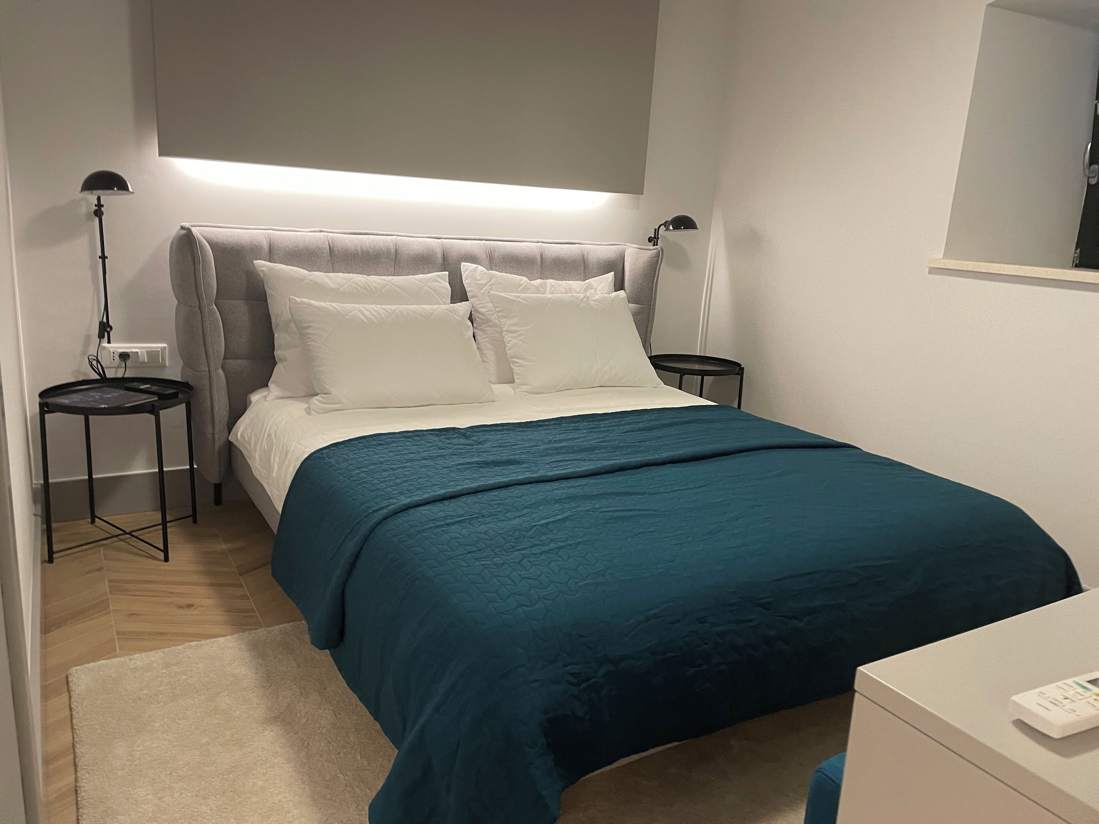 Quarto bem arrumado com cama, mesas de cabeceira e apoio para luminária.
