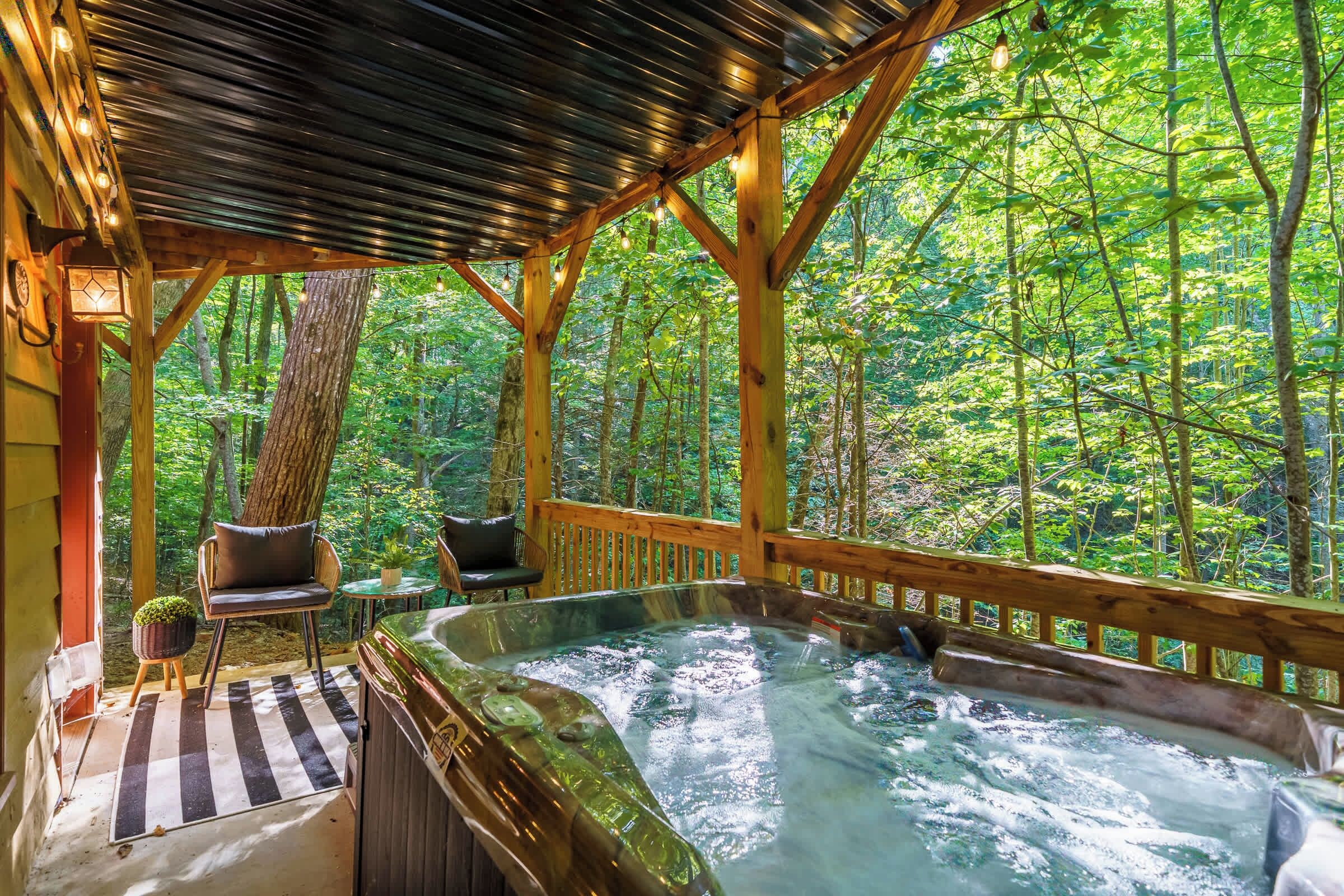 A hot tub in a wooden gazebo surrounded by a forest.