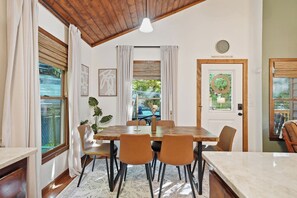 Un coin repas avec une table en bois, six chaises et une vue sur l’extérieur par une fenêtre.
