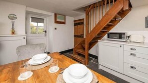 Ein Essbereich mit einem Holztisch, gedeckt für vier Personen, einem weißen Schrank mit Schubladen und einer Holztreppe.