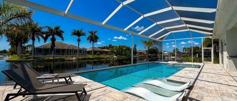 A pool area with lounge chairs, a covered patio, and a clear view of the surrounding landscape.
