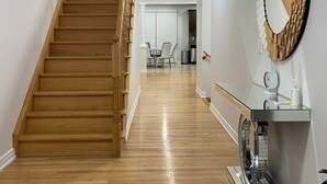 Un escalier en bois mène à un espace repas agrémenté d’un miroir moderne et d’un appareil électroménager encastré.