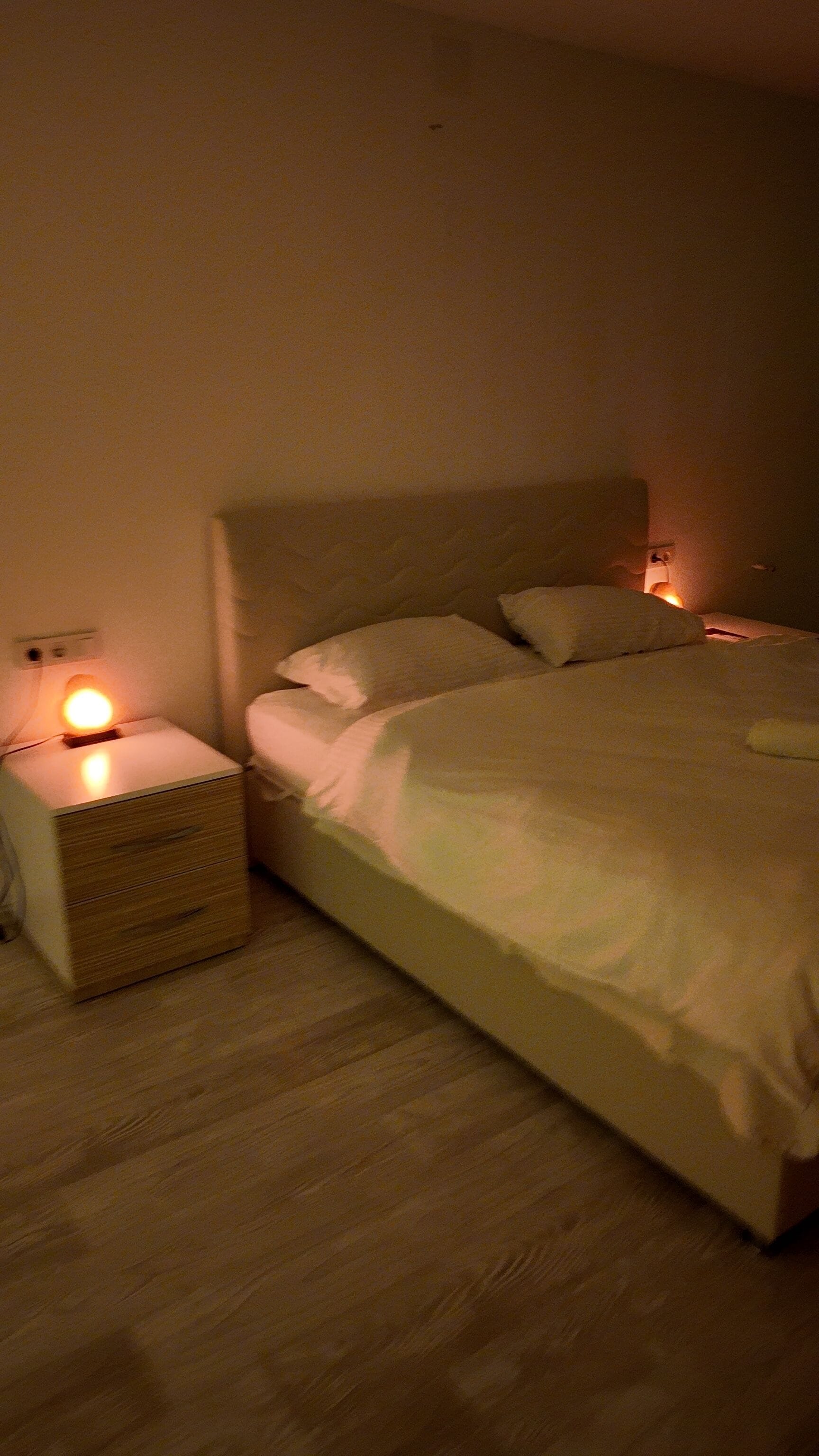 A bedroom with a bed, bedside table, and nightstand.