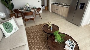 A modern living room with a sofa, coffee table, and dining area. - Poniente 201 – Tropical Garden Apartment with Pools near Dominicus Beach (Dominicus)