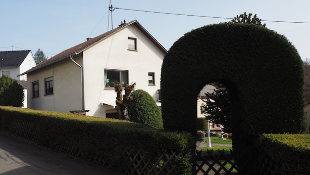 A residential house with a white exterior, a small window with a curtain, and a neatly trimmed hedge in front. - Vacation apartment Haus Junk am Lieserpfad (Daun)