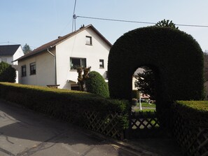 A residential house with a white exterior, a small window with a curtain, and a neatly trimmed hedge in front. - Vacation apartment Haus Junk am Lieserpfad (Daun)