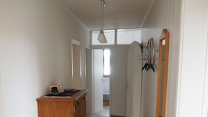 A hallway with a wooden cabinet, a potted plant, and a rug leading to a bedroom. - Vacation apartment Haus Junk am Lieserpfad (Daun)
