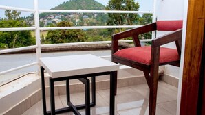 A balcony with a white table and a wooden chair with a red cushion. - Hotel OCCAZIA Homa Bay (Homa Bay)