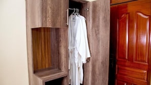 A wooden wardrobe with a hanging rod and a shelf. - Hotel OCCAZIA Homa Bay (Homa Bay)