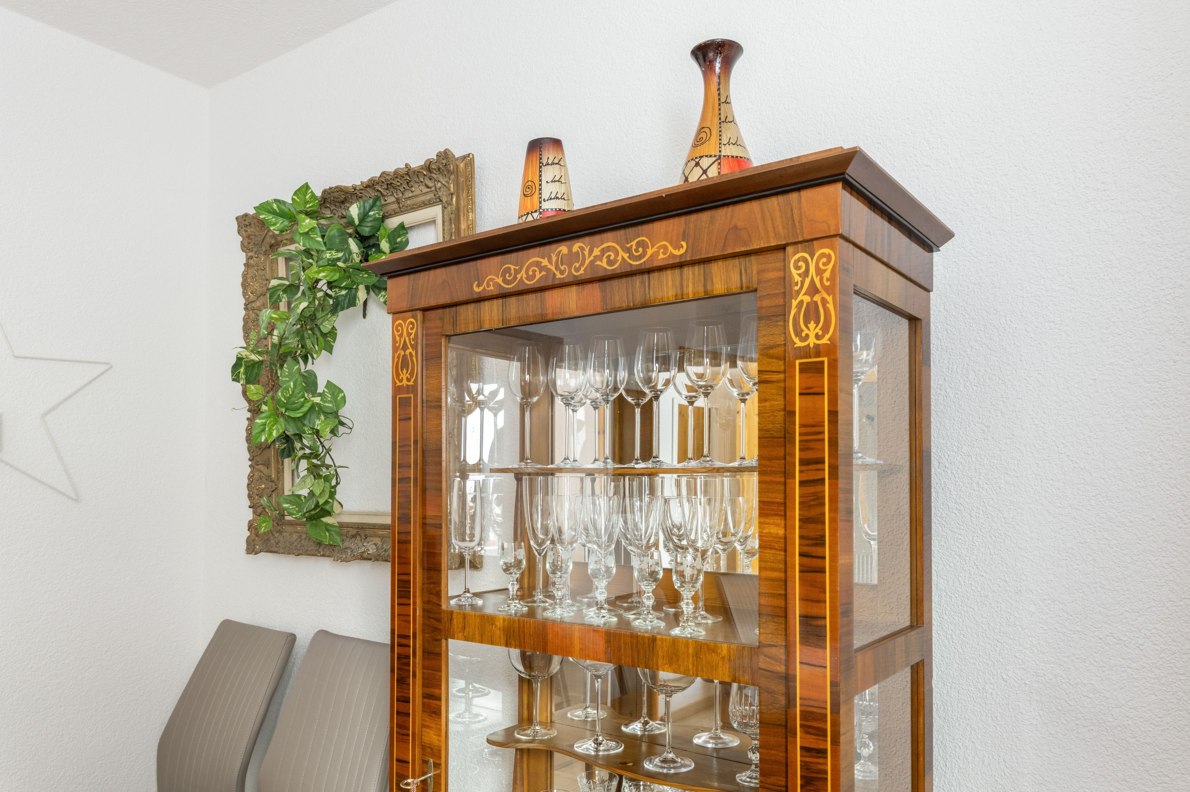 Un armario de madera con puertas de cristal que exhibe copas de vino.
