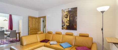 A modern living room with a sectional sofa, a coffee table, and a painting on the wall.