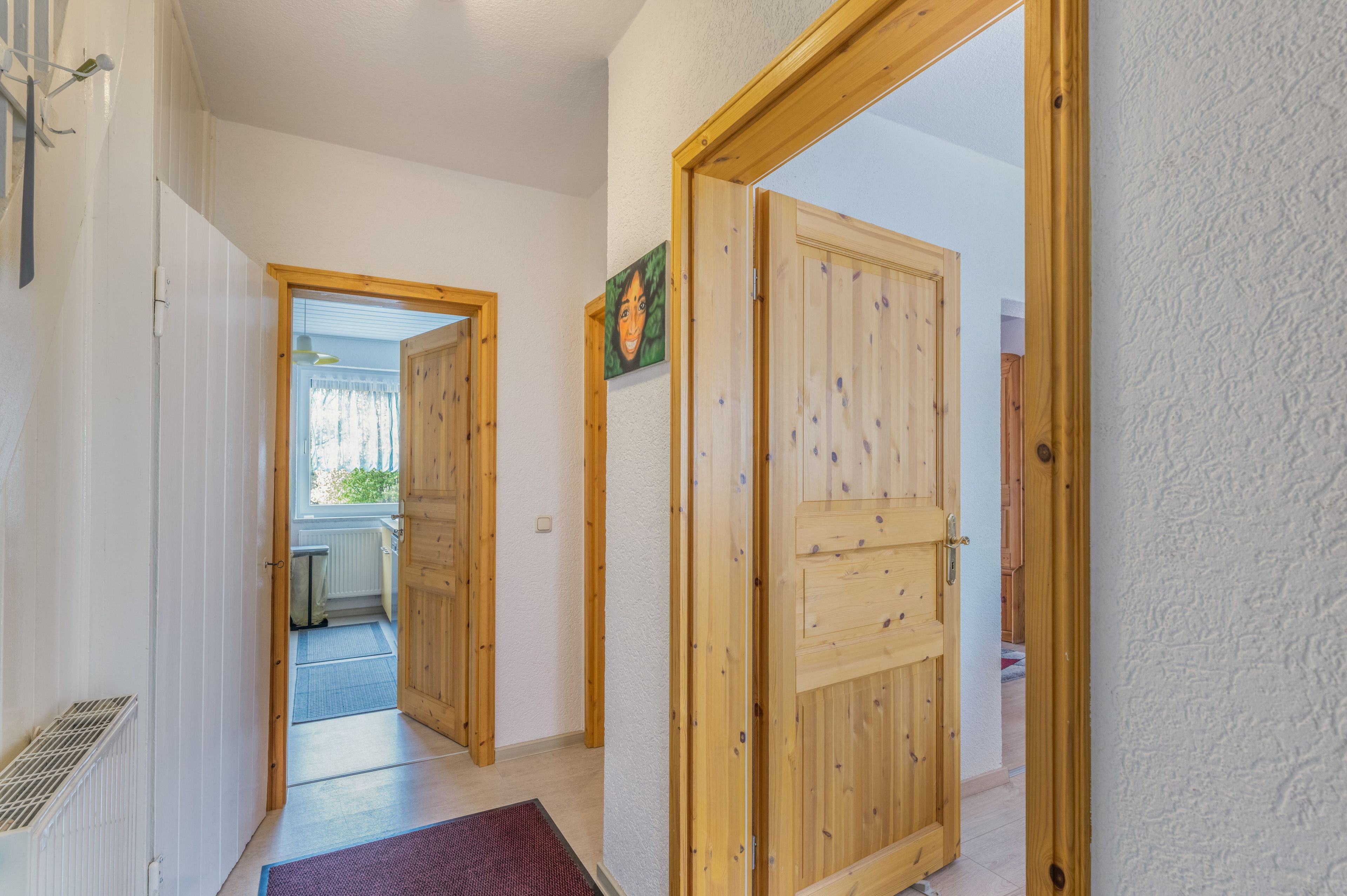 Un pasillo con puertas de madera, un radiador y una ventana con cortinas.