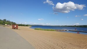 A sandy beach with a wooden structure, a dock, and a clear blue sky.
