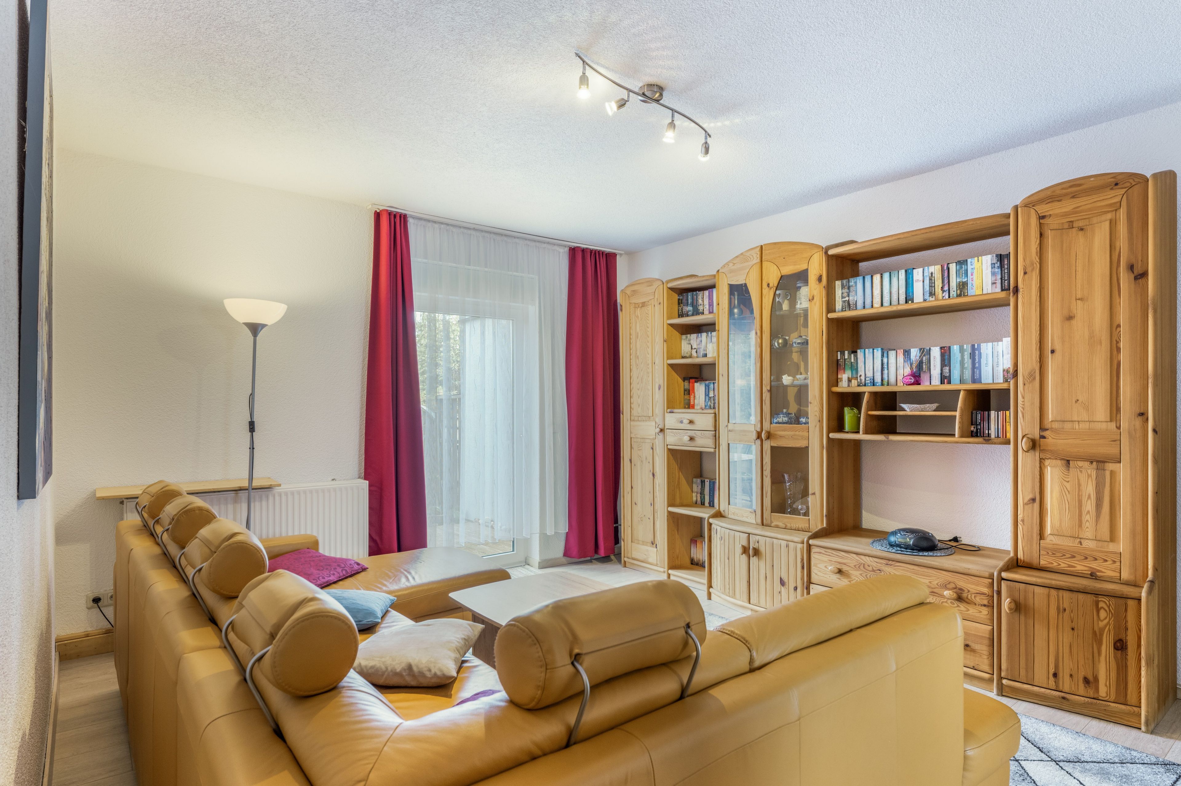 A living room with a sofa, a wooden bookshelf, and a floor lamp.