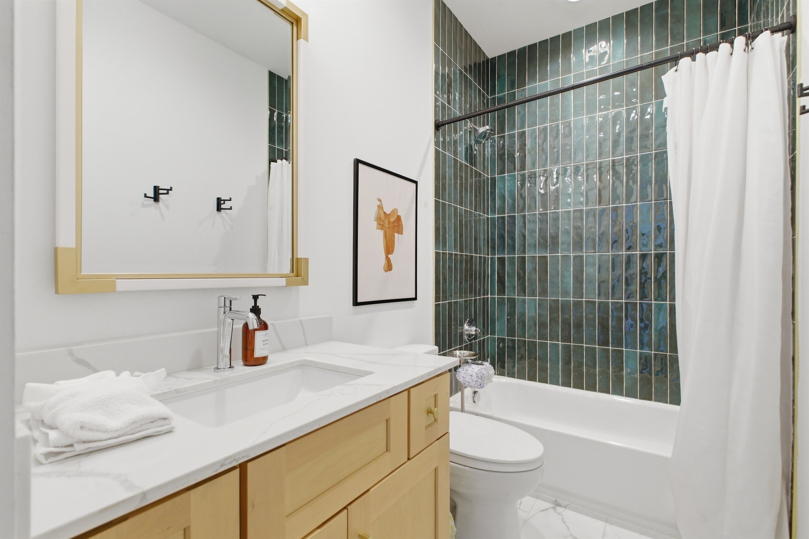 A modern bathroom with a large mirror, a sink, a toilet, and a shower with a curtain.