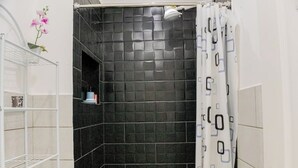 A shower area with black tiles, a white shower curtain, and a white tiled wall. - *comfortable loft in the center of Quetzaltenango (Quetzaltenango)