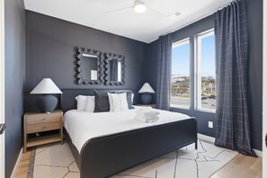Un dormitorio moderno con una cama grande, dos mesitas de noche, un espejo y vistas al exterior.