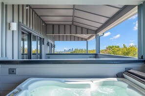 Una terraza moderna en la azotea con jacuzzi, ventanas amplias y vistas al horizonte de la ciudad.