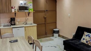 Un espacio habitable compacto con kitchenette, comedor y sofá.