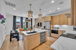 Una cocina moderna con una isla central, electrodomésticos de acero inoxidable y armarios de madera.