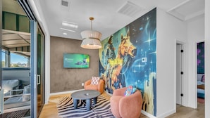 Un salon moderne agrémenté d’une grande fresque murale, de sièges confortables et d’un téléviseur diffusant le logo « IPVanish ».
