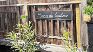 En træpergola med et skilt, der viser "Maison du bonheur", og et bambushegn.