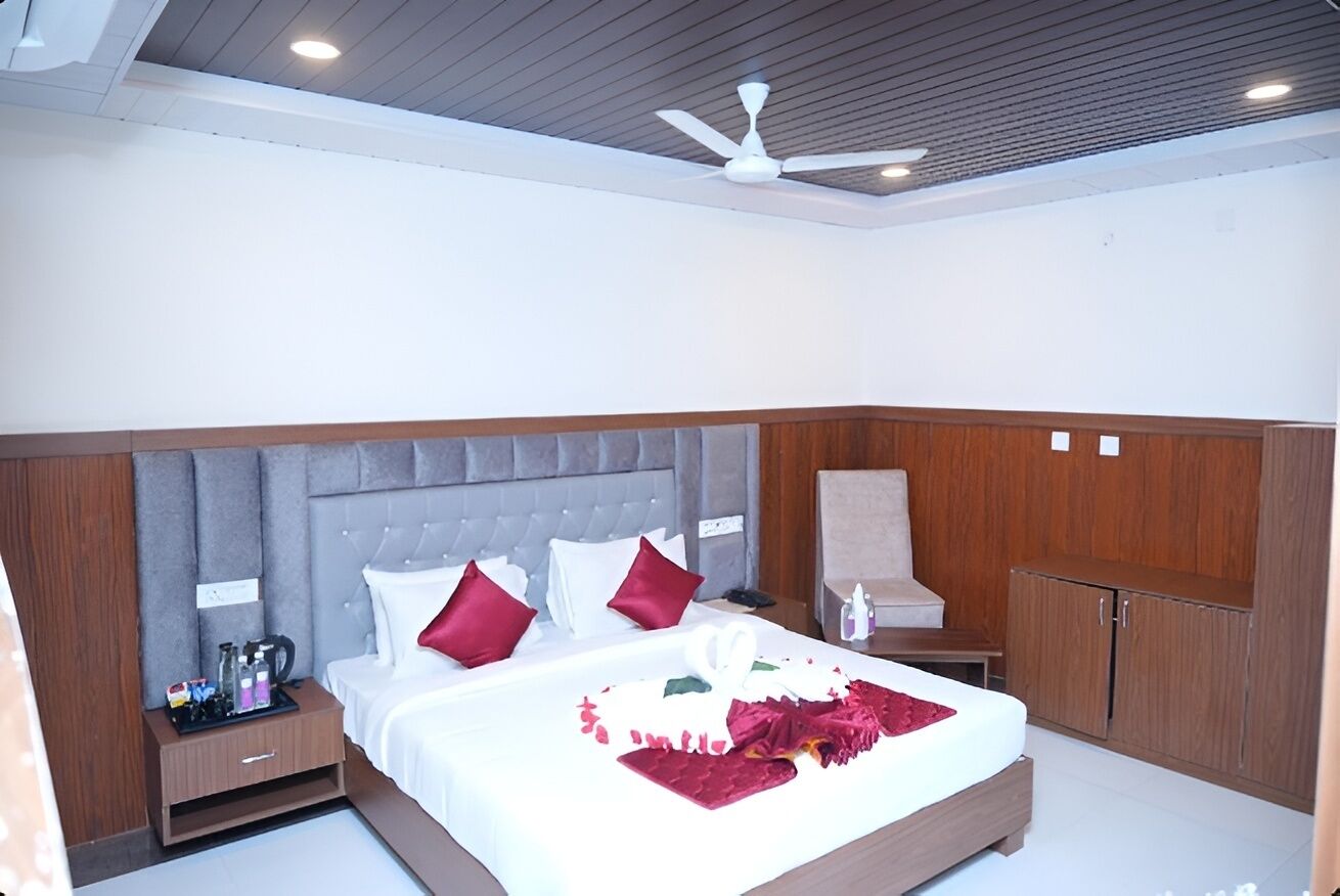 A bedroom with a large bed, a wooden wardrobe, a nightstand, and a ceiling fan.